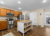 Thumbnail 11 of 20 - A kitchen with wooden cabinets and a white island.