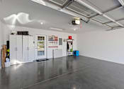 Thumbnail 12 of 20 - A spacious room with a grey floor and white walls, equipped with a ceiling lighting system and a few cabinets.