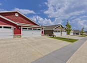 Thumbnail 2 of 19 - A red building with a white garage door is in front of a house.