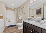 Thumbnail 14 of 19 - A bathroom with a white toilet, a white bathtub, a sink, and a mirror.