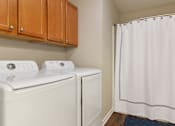 Thumbnail 16 of 19 - A white washing machine and dryer in a laundry room.