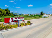 Thumbnail 18 of 19 - A sign for Redwood Apartment Homes sits in front of a road.