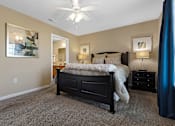 Thumbnail 12 of 19 - A bedroom with a bed, nightstand, and a ceiling fan.