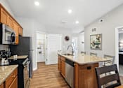 Thumbnail 5 of 19 - A kitchen with wooden cabinets and a granite countertop.