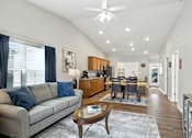 Thumbnail 9 of 19 - A modern living room with a grey sofa and a wooden coffee table.