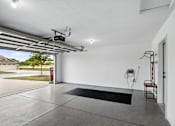 Thumbnail 18 of 19 - A garage with a black mat on the floor and a red fire extinguisher on the wall.