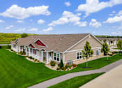 Thumbnail 3 of 19 - A house with a red roof and a brown roof is surrounded by green grass and trees.