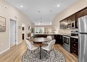 Thumbnail 6 of 19 - A modern kitchen with a dining table and chairs.