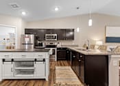Thumbnail 4 of 19 - A modern kitchen with dark brown cabinets and a white island.