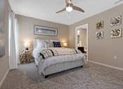 Thumbnail 6 of 19 - A bedroom with a large bed and a ceiling fan.