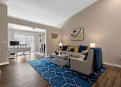 Thumbnail 13 of 19 - A living room with a blue rug and a white couch.