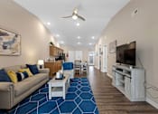 Thumbnail 7 of 19 - A living room with a blue carpet and a ceiling fan.