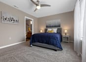 Thumbnail 14 of 19 - A bedroom with a bed, nightstand, and a painting on the wall.