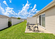 Thumbnail 12 of 19 - A patio with a table and chairs is surrounded by a white fence.