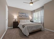 Thumbnail 18 of 19 - A bedroom with a bed, a ceiling fan, and a painting on the wall.