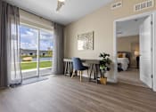 Thumbnail 15 of 19 - A room with a sliding glass door leading to a patio, a dining table with chairs, and a mirror on the wall.