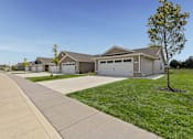 Thumbnail 2 of 19 - A tree stands in front of a house with a driveway leading to the garage.