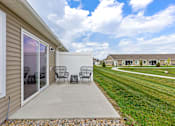 Thumbnail 4 of 19 - A patio with a table and chairs is in front of a house.