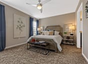 Thumbnail 11 of 19 - A bedroom with a bed, nightstands, and a ceiling fan.