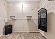 Thumbnail 13 of 19 - A walk-in closet with a black coat hanging on a hanger.