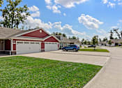 Thumbnail 1 of 19 - A blue car is parked in front of a red garage.