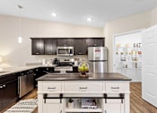 Thumbnail 5 of 19 - A kitchen with a black countertop and white cabinets.