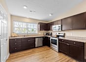 Thumbnail 6 of 19 - A kitchen with brown cabinets and stainless steel appliances.