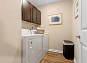 Thumbnail 17 of 19 - A laundry room with a washer and dryer and a basket of clothes.