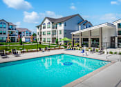 Thumbnail 1 of 33 - A swimming pool in front of a building with a black fence around it.