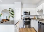 Thumbnail 12 of 25 - A modern kitchen with a stainless steel oven and white cabinets.