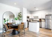 Thumbnail 13 of 25 - A modern kitchen with a dining table and chairs.