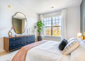 Thumbnail 21 of 25 - A bedroom with a bed, dresser, and mirror.