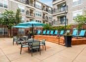 Thumbnail 9 of 25 - a patio with tables and chairs and umbrellas at an apartment building