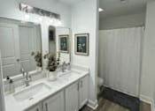 Thumbnail 17 of 21 - A bathroom with a white sink and a mirror above it.