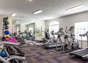 Thumbnail 6 of 21 - A gym with a variety of exercise equipment including treadmills, stationary bikes, and weight machines.