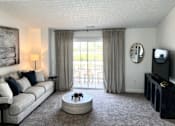 Thumbnail 8 of 21 - A living room with a grey couch, a coffee table, a television, and a painting on the wall.