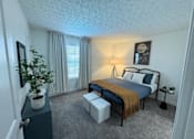 Thumbnail 12 of 21 - A bedroom with a bed, nightstand, and a potted plant.