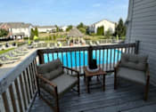Thumbnail 10 of 21 - A wooden deck with two chairs and a table overlooking a pool.