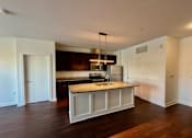 Thumbnail 2 of 18 - A kitchen with a granite countertop and a hanging light fixture.