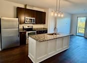 Thumbnail 1 of 18 - A kitchen with a granite countertop and stainless steel appliances.