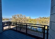 Thumbnail 5 of 18 - A balcony with a black railing overlooking a body of water.