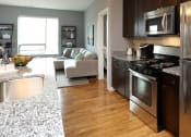 Thumbnail 2 of 12 - a kitchen and living room with stainless steel appliances and granite counter tops