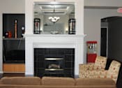 Thumbnail 3 of 12 - A living room with a fireplace and a chair.
