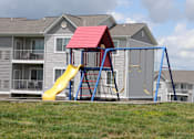 Thumbnail 8 of 13 - A red and yellow slide in front of a grey house.