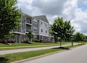 Thumbnail 11 of 13 - A large apartment building with a tree in front of it.