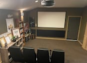 Thumbnail 12 of 12 - A home theater setup with a large screen and seating for four.