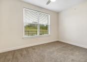 Thumbnail 47 of 63 - an empty bedroom with a window and carpeting at Vanguard Crossing, St. Louis, MO
