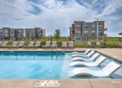 Thumbnail 34 of 36 - a swimming pool with chaise lounge chairs in front of an apartment building at Statesman Apartments, Wisconsin
