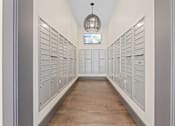 Thumbnail 45 of 52 - A long hallway with a chandelier and a row of mailboxes on the wall at Aster Apartments, Ohio