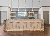 Thumbnail 3 of 52 - A kitchen with a bar area featuring a granite counter and bar stools at Aster Apartments, Beachwood, OH 44122
